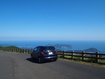 Car on road against clear blue sky