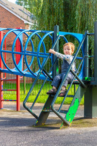 Portrait of smiling boy on steps leading to slide at playground