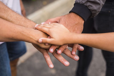 Midsection of friends stacking hands outdoors