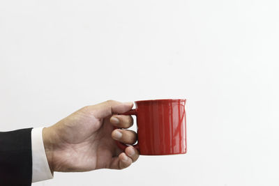 Midsection of man holding cup against white background