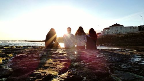 People relaxing on beach at sunset