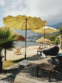 Deck chairs and parasols on beach against sky