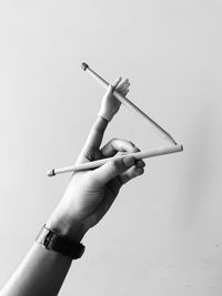 Low angle view of hand holding cigarette against white background