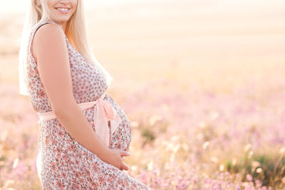 Happy pregnant woman standing on field