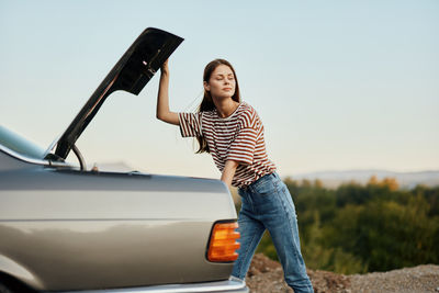 Rear view of woman using mobile phone while standing on road