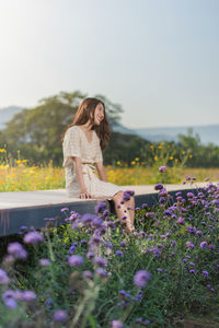 Smiling woman looking awau while sitting amidst flowering plants