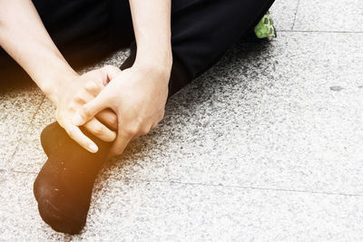 Low section of man holding leg on tiled floor