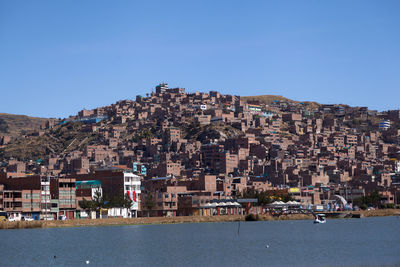 Townscape by sea against clear blue sky