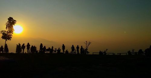 Silhouette people on beach against sky during sunset