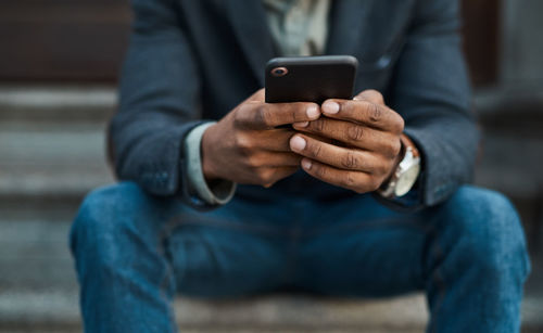 Midsection of man using mobile phone