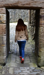 Rear view of woman standing against wall