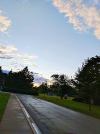 Road by trees against sky