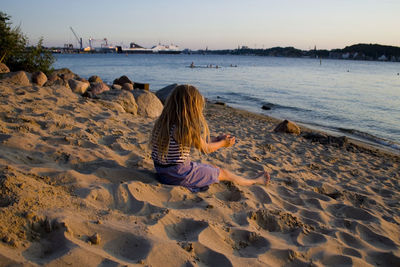 Rear view of girl playing with sand at beach