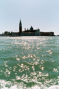 View of sea and buildings against clear sky