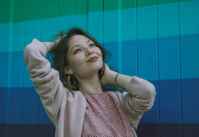 Portrait of young woman standing against wall