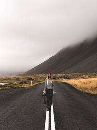 Woman standing on road against sky