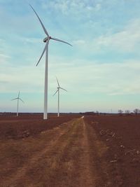 Windmills on landscape against sky