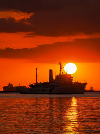 Silhouette boat in sea against orange sky