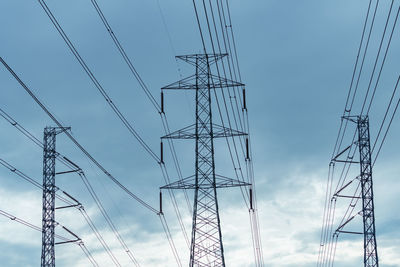 High voltage electric pylon and electrical wire against blue sky and clouds. 