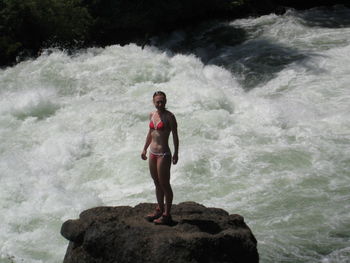 Woman standing on rock in sea