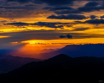 Scenic view of silhouette mountains against orange sky