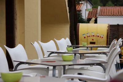 Empty chairs and tables in restaurant against building