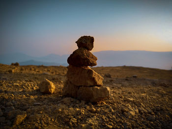 Stack of rocks on land against sky during sunset