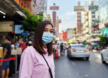 Portrait of young woman standing on street in city