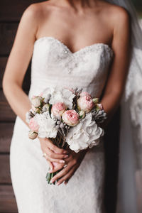 Midsection of bride holding bouquet