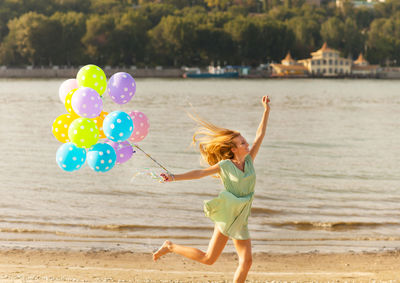 Full length of woman with balloons at beach