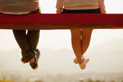 Low section of couple sitting on bench