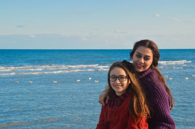 Portrait of mother and daughter against sea