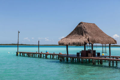 Pier over sea against clear blue sky