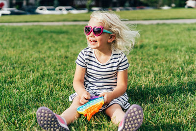 Girl wearing sunglasses sitting on field