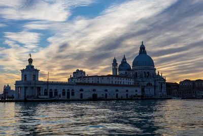 View of buildings at waterfront against cloudy sky