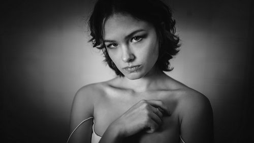 Portrait of young woman looking away against gray background