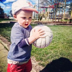 Cute boy holding volleyball in park