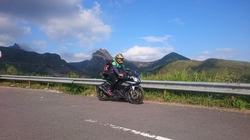 Man riding motorcycle on road against sky