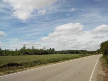 Empty country road against cloudy sky