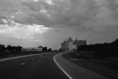 Road by buildings in city against sky