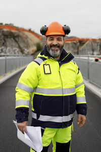 Portrait of male engineer in reflecting clothing standing on bridge