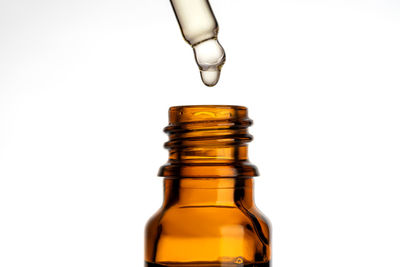 Close-up of hand holding bottle against white background