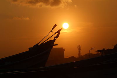 Silhouette boat moored in sea against orange sky. sunset between the boat captured on perfect timing
