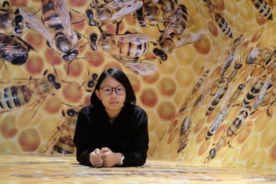 Portrait of girl sitting against honey bee wallpaper