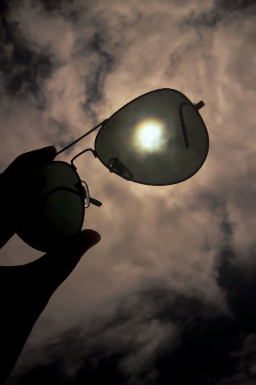 LOW ANGLE VIEW OF PERSON HAND HOLDING UMBRELLA AGAINST SKY