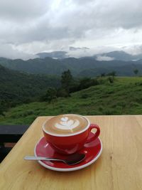 Coffee cup on table against mountains