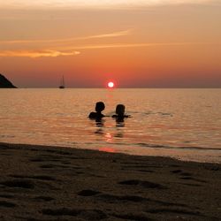 Silhouette people on beach against sky during sunset