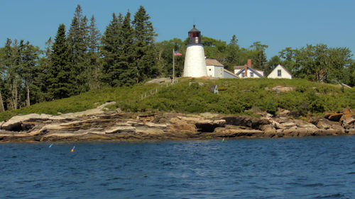 Lighthouse by sea against sky