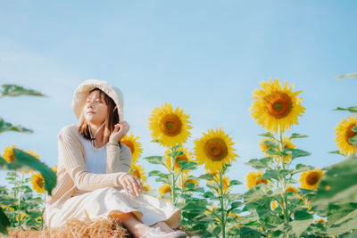 Portrait of woman by sunflowers against sky