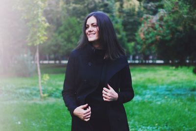 Young woman standing on grassy field in park